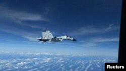 资料照片:美国印太司令部公布的视频显示中国海军一架歼-11战斗机2022年12月21日在南中国海的国际空域以不安全的方式拦截美国空军RC-135侦察机。