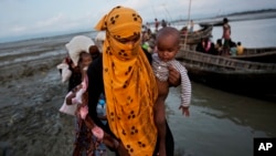 一名罗兴亚妇女带着一个小孩坐船穿过一条小河。(2017年9月21日)