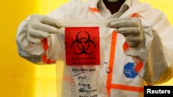 一名医务人员在展示新冠病毒检测试剂。