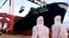 身穿防护服的中国海关人员在山东省青岛港检查一艘货轮。(2020年11月16日)