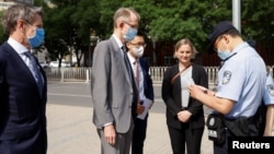 一名中国警察在北京市第二人民法院外查看澳大利亚驻华大使傅关汉 (Graham Fletcher)的身份证件。(2021年5月27日)