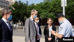 一名中国警察在北京市第二人民法院外查看澳大利亚驻华大使傅关汉 (Graham Fletcher)的身份证件。(2021年5月27日)