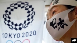 一名日本女子站在东京奥运会标识旁。(2021年4月10日)