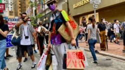 香港异见艺术家黄国才2020年7月1日,香港国安法实施第一日,在铜锣湾以”血拼”为名,打扮成来自中国大陆的”豪客”,手持多个写上国安法相关罪名的百货公司购物袋,表现对实施国安法的不安 (美国之音/汤惠芸)