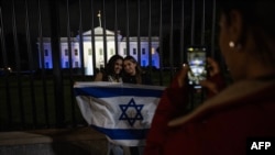 白宫2023年10月9日晚亮出以色列国旗的灯光,支持者们在大门前留影。(法新社)