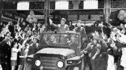 毛泽东(1893-1976)和林彪(1907-1971)1967年5月1日在敞篷吉普车上向在北京天安门广场庆祝五一节的群众挥手致意。