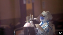 在印度的新德里,医护人员正在为新冠病人修理氧气罐。