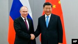 Tổng thống Nga Vladimir Putin (trái) bắt tay Chủ tịch Trung Quốc Tập Cận Bình trước cuộc hội đàm bên lề Hội nghị thượng đỉnh BRICS lần thứ 11, tại Brasilia, Brazil, vào ngày 12/11/2019. Ông Putin hôm 22/2 cho biết ông Tập sẽ sớm thăm Moscow.