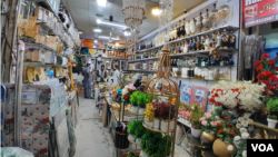 11月24日巴基斯坦白沙瓦卡尔卡诺市场的一家家居用品店里,一位家居装饰零售商正忙着与买家谈判交易 (美国之音/沙基尔)