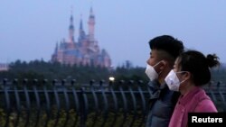 戴着口罩的上海市民从春节期间关闭的迪斯尼乐园旁走过。(2020年1月24日)