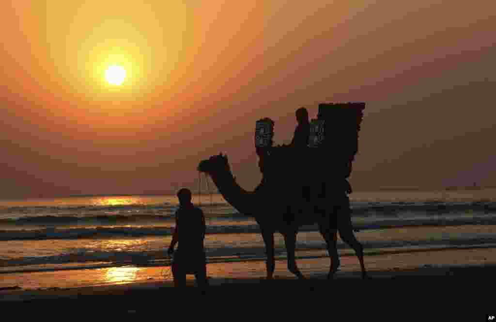 A Pakistani rides a camel on a beach during the last sunset of 2018, in Karachi, Dec. 31, 2018.