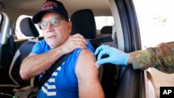 消防员杰弗里·狄龙(Jeffrey Dillon)坐在车里拉起衬衫袖子,在德克萨斯州达拉斯县卫生局设立的疫苗现场接种辉瑞疫苗加强剂。(2021年11月30日美联社照片)