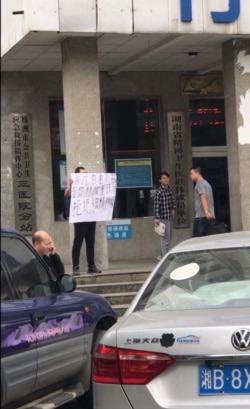 2019年10月22日,邱孝斌在湖南株洲三医院门前举牌声援“泼墨女孩”董瑶琼