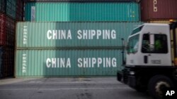 资料照:在乔治亚州萨瓦纳港,一辆卡车驶过中国海运集团的集装箱。(2018年7月5日)