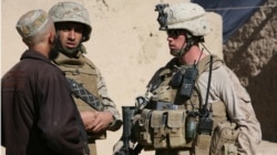 资料照片:一名美国海军陆战队下士在翻译的帮助下在阿富汗某镇与一名村民交谈。(2009年12月6日)