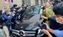 代表李宇轩的事务律师陈天立及大律师罗达雄乘车离开法院大楼时,被大批记者包围追访,场面一度混乱,后来有警车协助开路离开 (美国之音/汤惠芸)