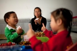 中国官方2011年10月29日宣布允许所有夫妻生育二胎。图为浙江诸暨35岁的王女士和她的两个孩子在家中。(2011年10月17日资料照。)