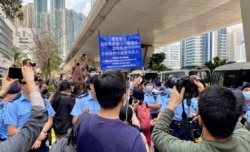 大批在场戒备的警员多次向西九法院大楼外排队的市民高举蓝旗及紫旗,警告聚集的市民涉嫌非法集结,高呼的口号涉嫌违反国安法 (美国之音/汤惠芸)