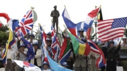 纪念仁川登录56周年时,韩国韩战老兵在麦克阿瑟塑像下挥舞着参战的16国旗帜