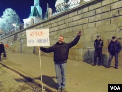 3月份在莫斯科红场举行了吞并克里米亚一周年的庆祝活动。一名参加者手举标语牌:克里米亚是俄罗斯的 (美国之音白桦)