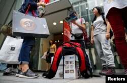 2016年10月4日,中国游客在日本东京银座购物区的一条街上等待巴士。