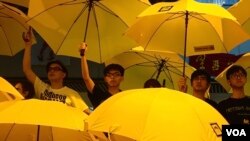 资料照:黄之锋和周永康与其他“雨伞运动”领袖一起在集会上撑开黄色雨伞。一个月前,警方向争取民主的抗议人群发射催泪弹。(2014年10月28日)