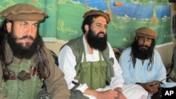 FILE - Pakistani Taliban spokesman Shahidullah Shahid, center, flanked by bodyguards, talks to reporters at undisclosed location, Pakistani tribal area of Waziristan, Oct. 5, 2013.