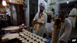 资料照片:2015 年 7 月 7 日星期二,巴基斯坦拉瓦尔品第,一名巴基斯坦小贩在为穆斯林斋月黎明前的餐食“sehri”准备牛奶拉西。