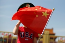 一名站在北京天安门广场的小男孩身穿美国T恤手拿中国国旗。(2019年5月7日)