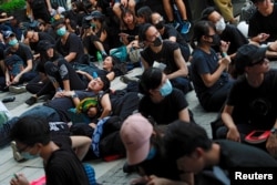 示威者2019年6月21日在香港举行的示威活动中坐在或躺在地上,他们要求香港领导人下台并撤回引渡法案。