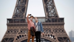 游客戴着口罩在埃菲尔铁塔前留影(路透社)