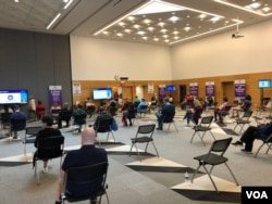 资料照片:在美国卫生当局宣布暂停使用强生新冠疫苗的一天前,人们在马里兰州一家社区学院设置的大型新冠疫苗接种站接种强生疫苗之后坐在观察区内。(2021年4月12日)