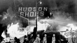 资料照片- 消防员在洛杉矶瓦茨区的骚乱中与一家鞋店发生的大火搏斗。(1965年8月14日)美联社