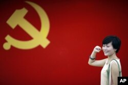 在上海的中共第一次代表大会会址,一名女子在中国共产党党旗下摆出宣誓姿势 (2012年7月1日)