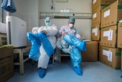 湖北武汉红十字会医院的医护人员在进入新冠病毒隔离病房前在穿戴防护用品。(2020年2月24日)