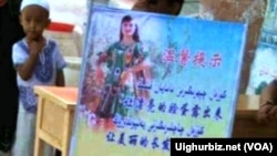 喀什街头的一个维吾尔男孩站在一幅宣传画后面。地方当局将维族妇女带面纱头巾归 为陋俗。(图片来源:维吾尔在线)