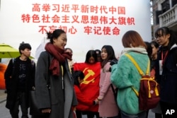 资料照:上海大学生在一幅宣传习近平的大标语前照相后将一面中共党旗收起来。(2017年11月19日)