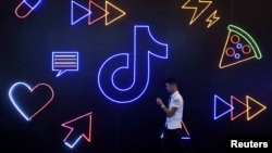 资料照:一名男子手持手持走过TikTok的标识。(2019年10月18日)