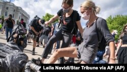 资料照片:在明尼苏达州州议会前的哥伦布雕像被推到后,示威者用脚踩倒地的雕像。(2020年6月10号,美联社)