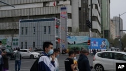 资料照片:人们走过新疆首府乌鲁木齐的一处警察站。(2021年4月21日)