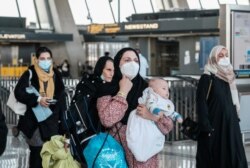 阿富汗难民抵达华盛顿附近的杜勒斯国际机场后登上接送他们前往受理中心的巴士。(2021年8月28日)