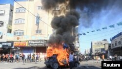 2023年10月7日,在加沙地带北部,一名巴勒斯坦男孩在一辆燃烧的以色列车辆旁边做出反应,这辆车辆是巴勒斯坦枪手渗透到以色列南部地区后带到加沙的。(路透社)