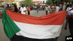 资料照:苏丹妇女2019年6月30日在首都喀土穆的集会上举着国旗游行。