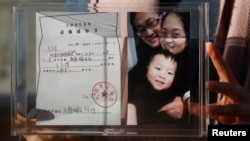 资料照:中国维权律师王全璋的妻子李文足手举全家福照片和天津警方的逮捕通知书。(2018年12月17日)