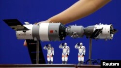 资料照: 在酒泉卫星发射中心展示的中国神舟9号飞船与三名中国宇航员的模型。(2012年6月15日)