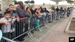 Những người tìm cách xin tị nạn tại Tijuana, Mexico, đang nghe gọi tên trong một danh sách chờ để đệ đơn xin tị nạn tại cửa khẩu ở San Diego, Mỹ (ảnh chụp ngày 26/9/2019)
