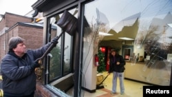 2014年11月26日,密苏里州弗格森的一家店主夫妇一起清除昨天晚上抗议者留下的涂污。