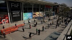 人们在伦敦西部的乐购超市连锁店外排队购物,他们站在胶带后面遵守社交距离,试图阻止冠状病毒的传播(2020年4月10日)。