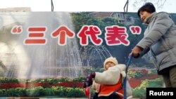 2002年11月28日,北京的一位母亲推着婴儿走过“三个代表”思想的宣传牌。中共说“三个代表”思想是江泽民的重要理论贡献。民间把“三个代表”思想和“资本家入党”联系起来。