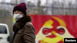 一名戴着口罩的男子走过上海街头一处中共徽标的图案。(2020年1月28日)